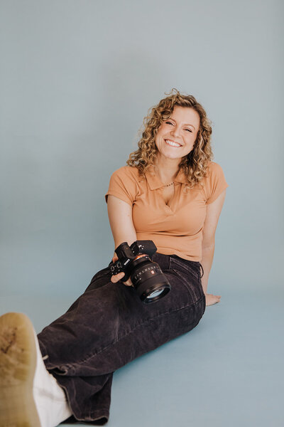 Megan Morris sits with her legs crossed and holds her camera in her lap