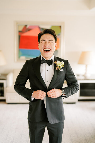 Laughing groom in tuxedo at Lotte New York Palace Wedding