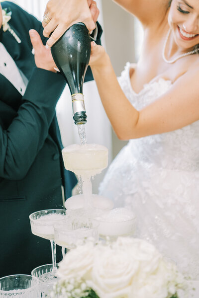 Close up image of bride pouring champagne onto a champagne tower