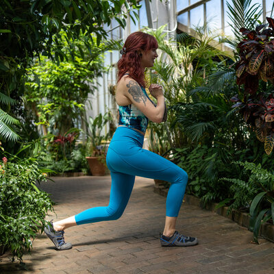 a woman in blue workout clothes does a bodyweight lunge to point towards fitness resources