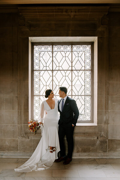 newlyweds in front of city hall window