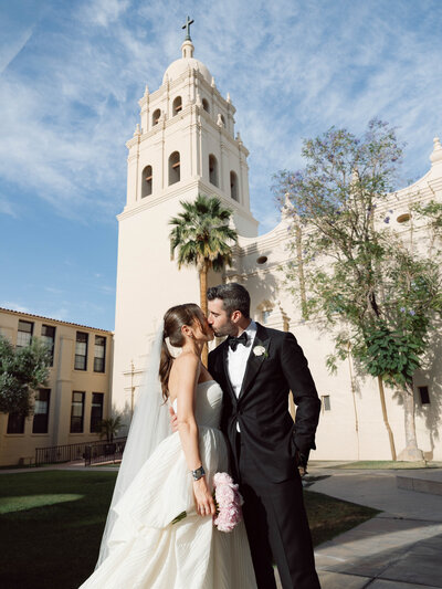 Bride in off-the-shoulder gown and cathedral veil walking along the stone paths of the Arizona Biltmore, captured in fine art documentary wedding photography.