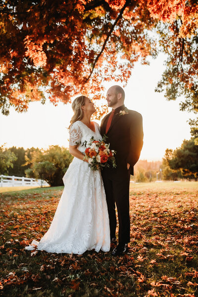 Wedding Photographer in Salem, couple standing under a tall tree, looking at each other