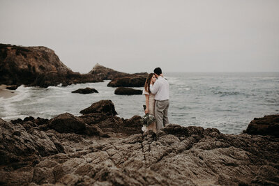 Bride & Groom holding each other on a rocky coast