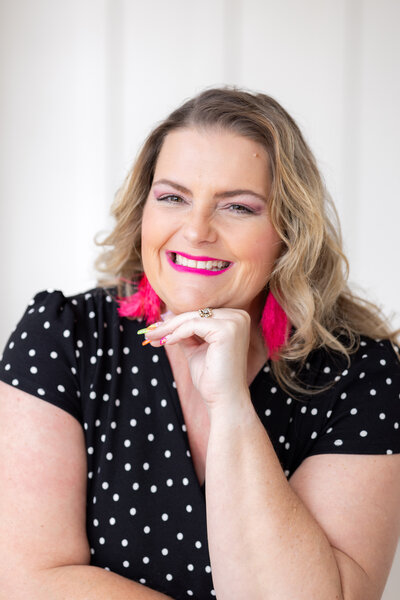 woman in black with pink earrings smiling at camera