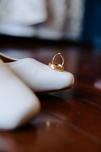 Wedding rings styled on the brides white wedding shoes during a North Augusta SC wedding, captured by KateLens Photography.