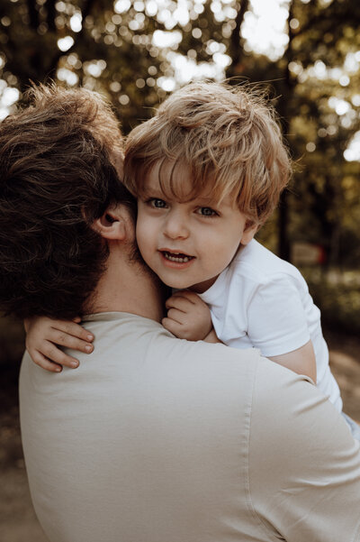 Papa en zoontje omhelzen elkaar tijdens gezinsshoot 