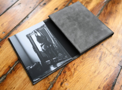 3 image grey leather folio, partially opened, revealing a photo of a woman wearing lingerie standing up against a mirror. 