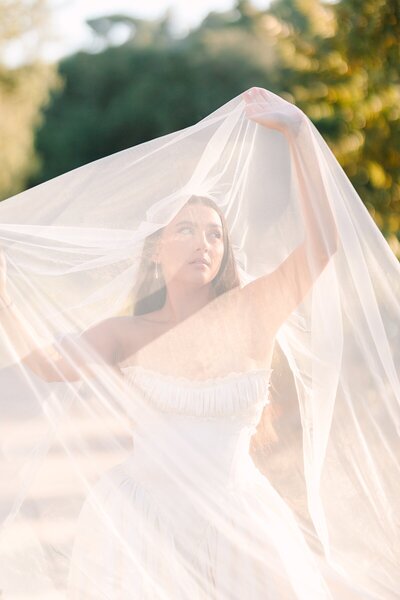Bride under her veil looking into the sunset as golden light streams onto her face at Monserate Winery in Fallbrook, California.