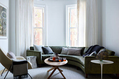 A Boston brownstone interior design project featuring a custom curved sofa, a mid-century modern chair, and modern interiors in a historic home.