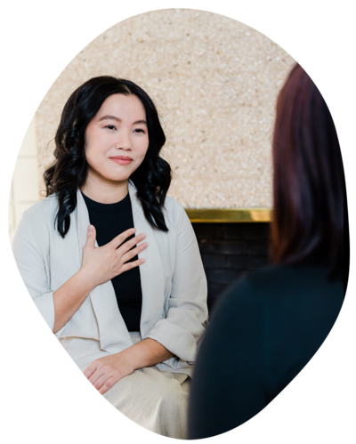 Joanne Lai the somatic therapist sitting with her hand over her heart