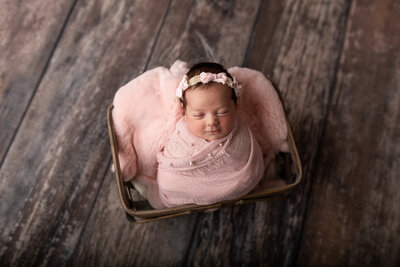 Newborn girl posed in a wood crate for a studio newborn session
