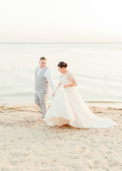 bride and groom walking hand in hand on beach in florida