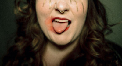 A person with smudged makeup and their tongue out.