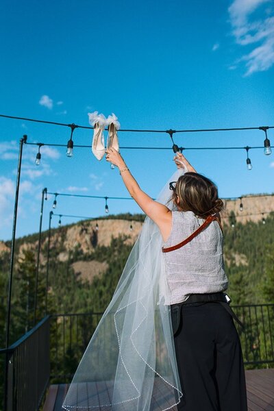 New Mexico elopement photographer explores the Red River area with her child, standing beside a mountain stream and towering cliffs under a bright summer sky.