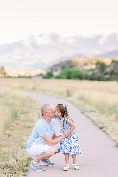 engaged couple sitting on wooden fence kissing