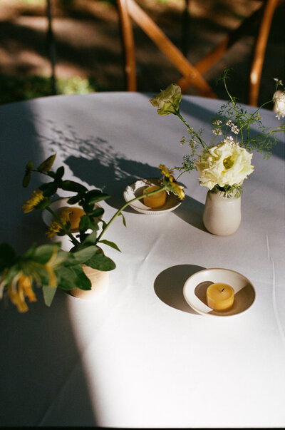 Simple floral arrangement and candles with shadows cast over the table for Austin wedding