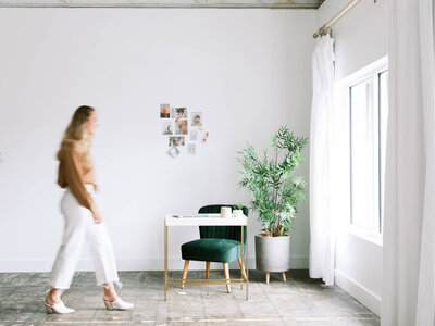 Woman walking in an office with a white desk and green chair