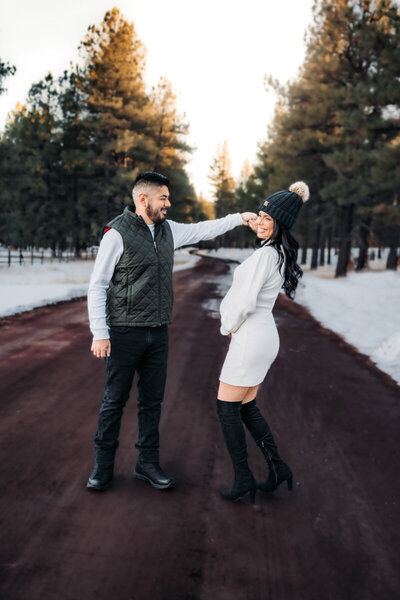 Expecting mom dancing with her husband during a maternity session in Flagstaff, Arizona with snowfall.