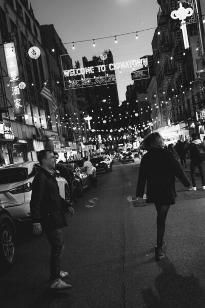 a couple walking under a "welcome to chinatown" sign in new york city