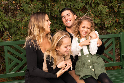 Family of four laughing together during their family photos