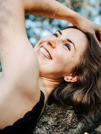 Outdoor Boudoir Shooting, lächelnde Frau auf einem Baum