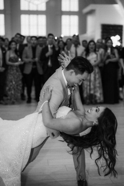 Black and white image of a bride and groom having their first dance looking at each other