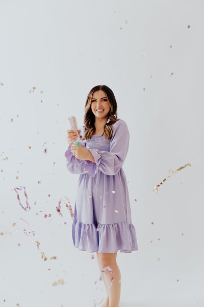 Caitlin wearing a purple dress and popping confetti for her new brand photoshoot