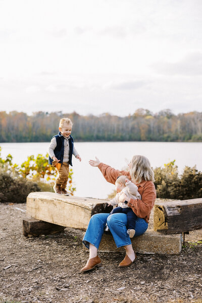 mom reaching out for son walking a log during family photos in Indianapolis