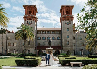 A bride and groom hold hands at their St. Augustine wedding in front of the Lightner Museum