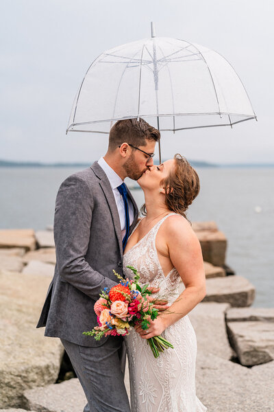 A couple during their New England Elopement on the coast of Maine, kissing after just getting married.