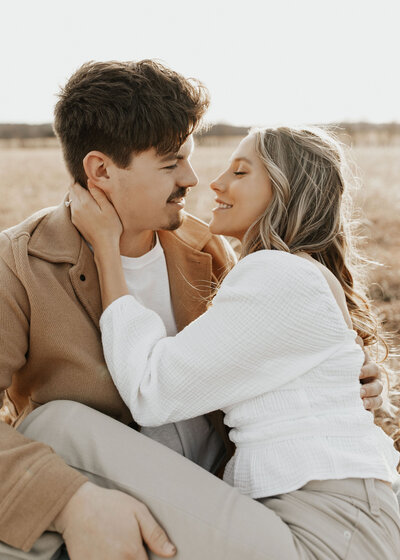 Couple going in for a kiss while sitting in golden field
