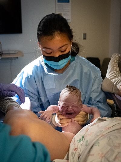 A doctor just "caught" a baby and is about to set the newborn on the mother's chest at Overlake Childbirth Center in Bellevue, WA.