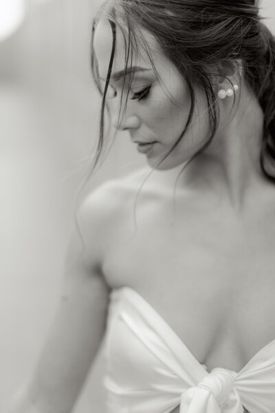 Black and white close-up of a modern bride in a knotted silk gown, softly lit and styled for an editorial bridal portrait with a cinematic, romantic aesthetic.