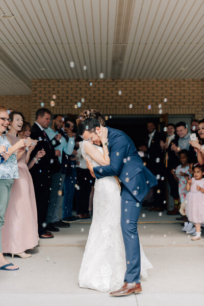 Bride and Groom hug each other as they exit through bubbles at their Indianola IA Wedding. Photo by Anna Brace who specializes in wedding photography in Des Moines IA.
