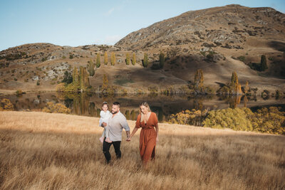 a family walking in the field holding hands while having a family photography session in Queenstown