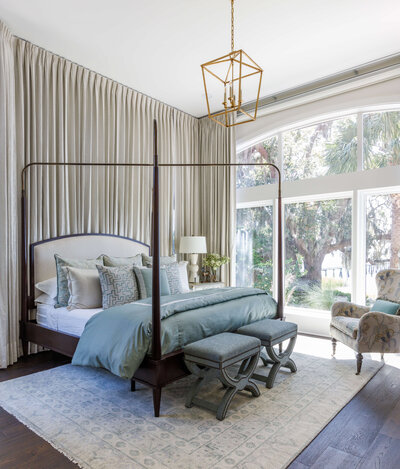 A master bedroom with high ceilings, dark wood floors, and a dark wood canopy bed