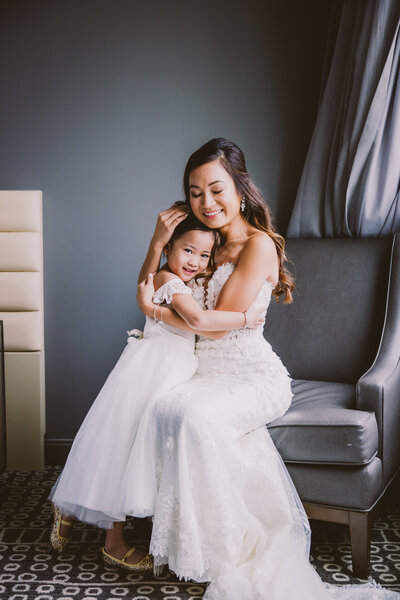 Vietnamese christian bride in a white dress hugging the flower girl before the wedding