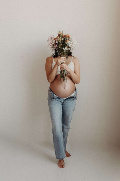 Gorgeous Black Woman  holds her husbands hands that are resting on her pregnant belly during a studio session.