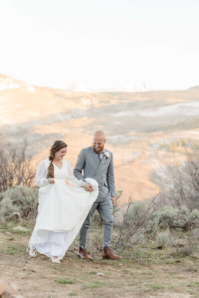 Bride and groom walking hand in hand during outdoor destination wedding in the mountains, captured by Destination Wedding Photographer.