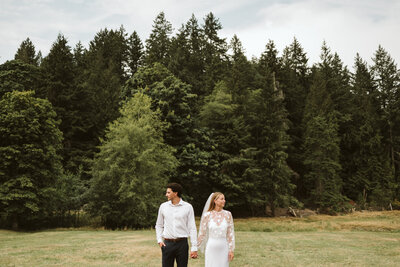 A couple standing side by side in a field on Bowen Island, where they had their intimate wedding.