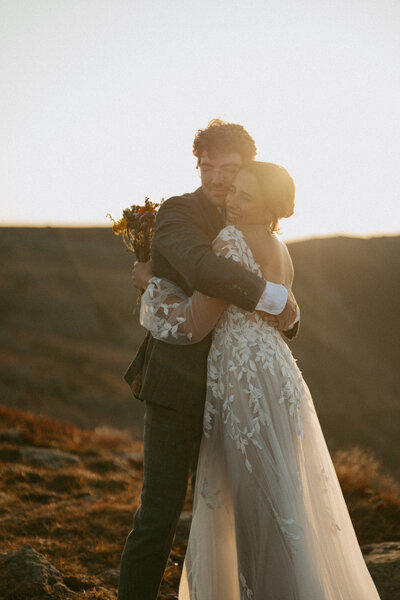 An elopement couple hugging on the summit of Mount Monroe in the Presidential Mountains of New Hampshire as the sun rises
