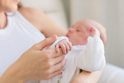 Newborn photos of a mother holding her new baby girl in her room by her crib
