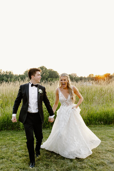 Bride and groom joyfully run through a field after their wedding