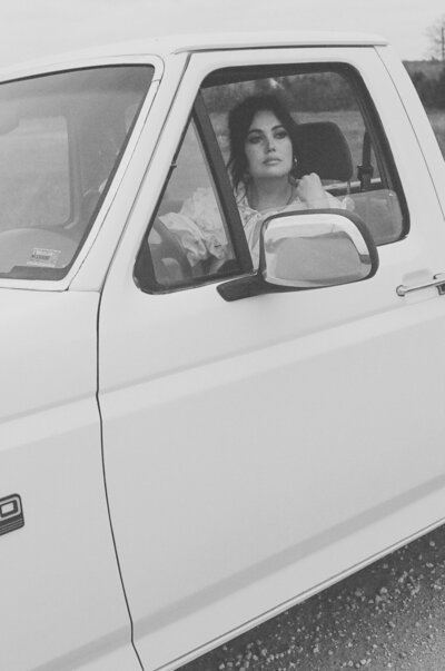 woman standing beside a vintage white truck in Kansas wearing a ruffled dress during a peaceful lifestyle session


