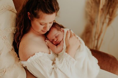 A new mother cuddles her newborn against her chest and softly rubs the baby's back