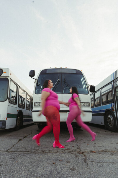 two women walking in front of buses