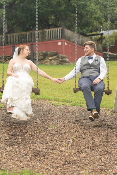 A wedding couple sits and swings  while holding hands.
