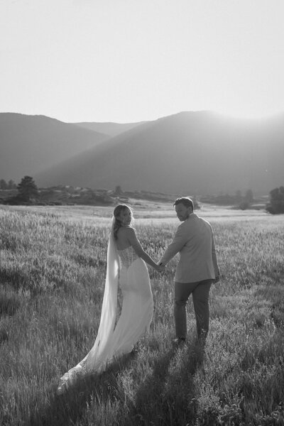 bride & groom walk together through the woods in Colorado on wedding day