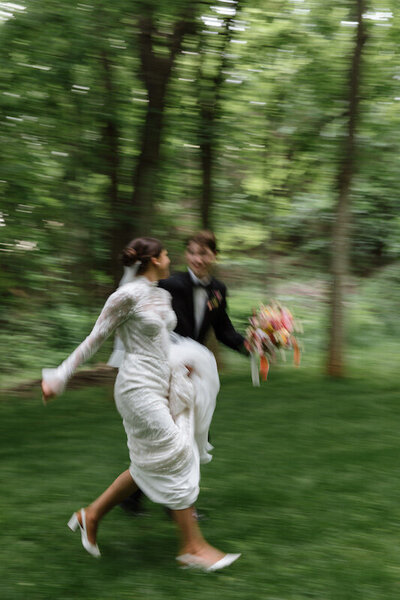 Bride and groom run together in a forest